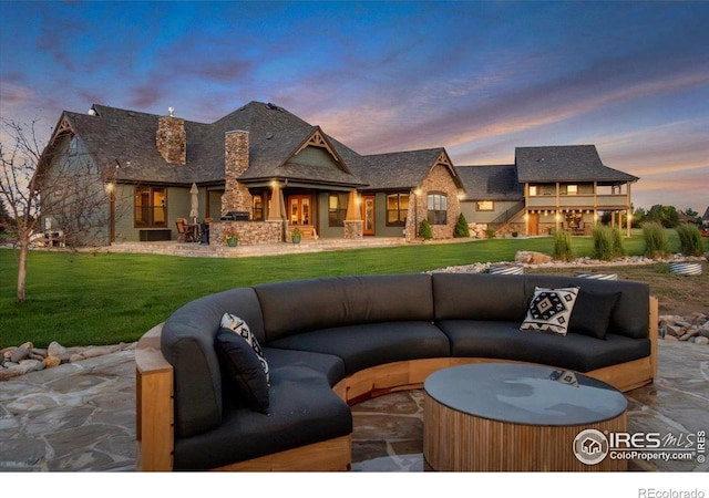 37021 Kingfisher Ct, Severance, CO 80550 - back of property at dusk with a hot tub, an outdoor hangout area, a patio, and a yard
