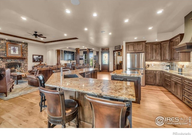 37021 Kingfisher Ct, Severance, CO 80550 - kitchen with freestanding refrigerator, a large island, a ceiling fan, decorative backsplash, and recessed lighting