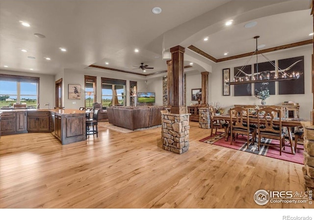 37021 Kingfisher Ct, Severance, CO 80550 - living room featuring decorative columns, arched walkways, light wood-type flooring, a raised ceiling, and crown molding