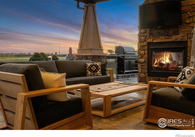 37021 Kingfisher Ct, Severance, CO 80550 - patio terrace at dusk with a patio, an outdoor living space with a fireplace, and area for grilling
