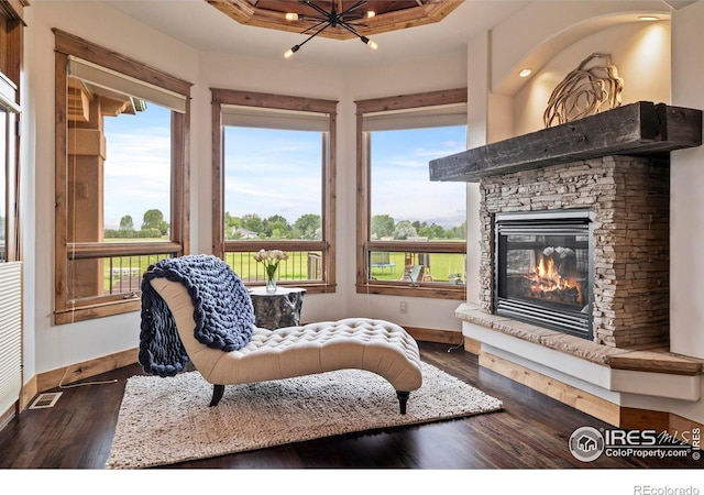 863 Riparian Way, Fort Collins, CO 80524 - sitting room featuring a stone fireplace, dark wood-type flooring, a chandelier, and a tray ceiling