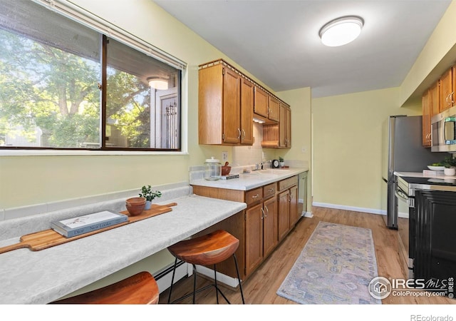705 E Drake Rd Unit 40, Fort Collins, CO 80525 - kitchen featuring stainless steel appliances, light wood-style floors, light countertops, a baseboard heating unit, and brown cabinetry