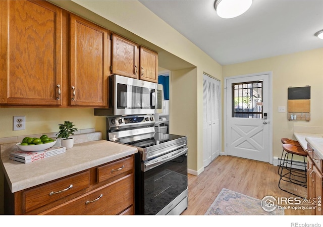 705 E Drake Rd Unit 40, Fort Collins, CO 80525 - kitchen featuring appliances with stainless steel finishes, brown cabinets, and a baseboard heating unit