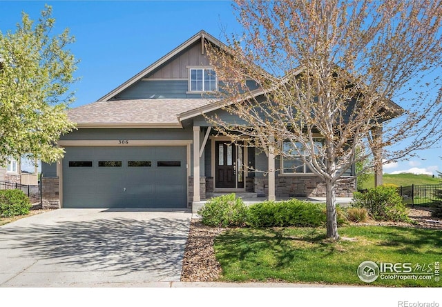 306 Baja Dr, Windsor, CO 80550 - craftsman house with a garage, concrete driveway, stone siding, covered porch, and roof with shingles