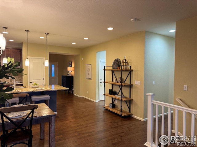 306 Baja Dr, Windsor, CO 80550 - kitchen featuring dark wood-style floors, recessed lighting, light stone counters, pendant lighting, and a kitchen bar