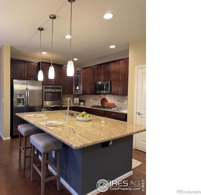 306 Baja Dr, Windsor, CO 80550 - kitchen with stainless steel appliances, dark wood-style floors, dark brown cabinets, tasteful backsplash, and a breakfast bar