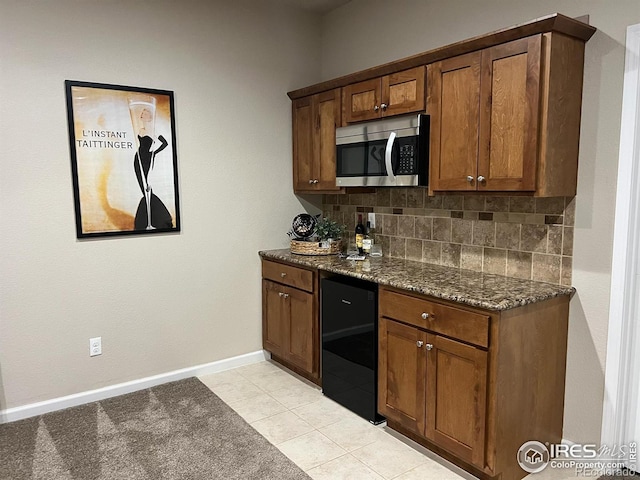 306 Baja Dr, Windsor, CO 80550 - kitchen with stainless steel microwave, backsplash, dark stone countertops, light tile patterned floors, and black dishwasher
