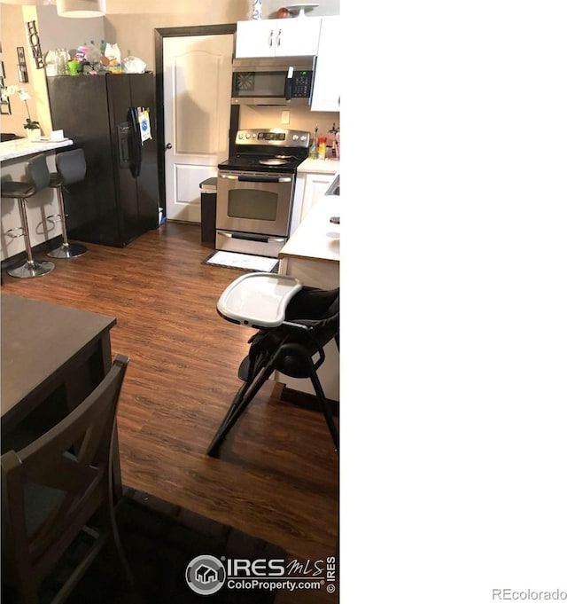 3200 Claremont Ave, Evans, CO 80620 - kitchen with stainless steel appliances, dark wood-style floors, white cabinetry, light countertops, and a breakfast bar