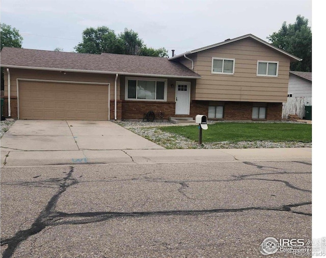 3200 Claremont Ave, Evans, CO 80620 - split level home featuring brick siding, an attached garage, concrete driveway, and a front yard