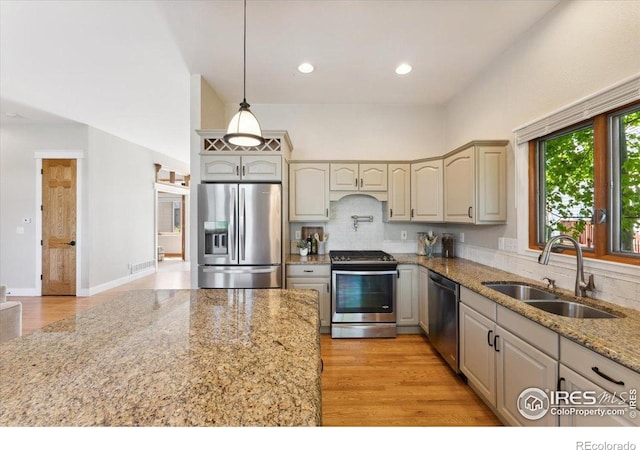 1206 Canvasback Ct, Fort Collins, CO 80525 - kitchen featuring stainless steel appliances, tasteful backsplash, hanging light fixtures, light stone countertops, and light wood-type flooring