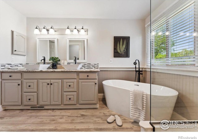 1206 Canvasback Ct, Fort Collins, CO 80525 - full bathroom featuring double vanity, a freestanding bath, wood finished floors, and a wainscoted wall