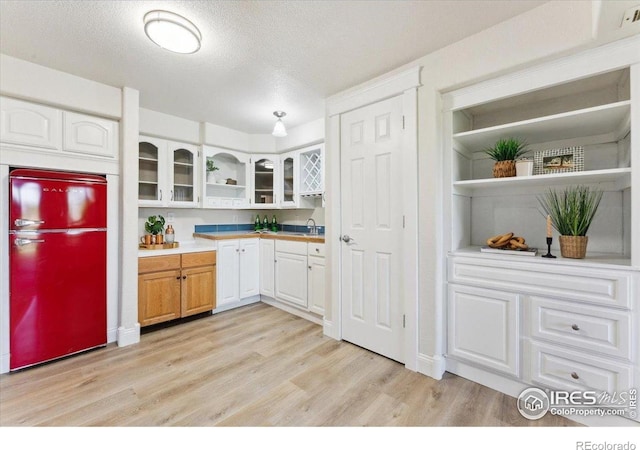 1206 Canvasback Ct, Fort Collins, CO 80525 - kitchen featuring fridge, open shelves, light wood-style floors, glass insert cabinets, and white cabinets