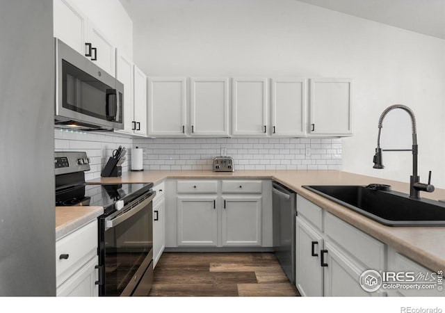 452 Mt Sherman Ave, Severance, CO 80550 - kitchen with appliances with stainless steel finishes, dark wood finished floors, backsplash, white cabinetry, and vaulted ceiling