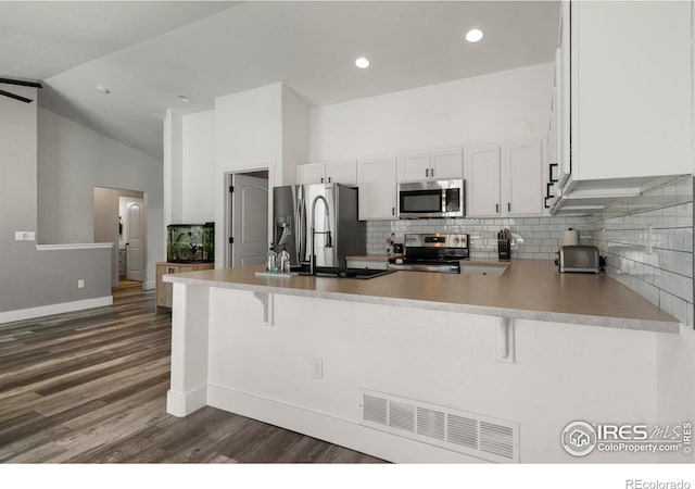 452 Mt Sherman Ave, Severance, CO 80550 - kitchen with appliances with stainless steel finishes, dark wood-style floors, a peninsula, tasteful backsplash, and lofted ceiling