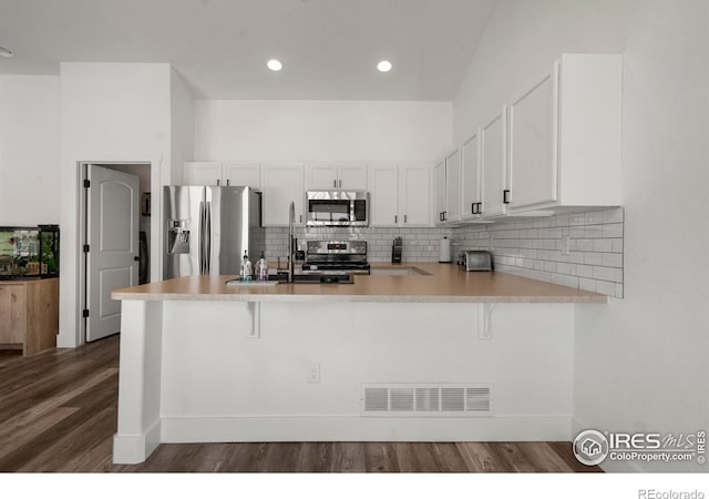 452 Mt Sherman Ave, Severance, CO 80550 - kitchen with appliances with stainless steel finishes, white cabinetry, a peninsula, a breakfast bar, and recessed lighting