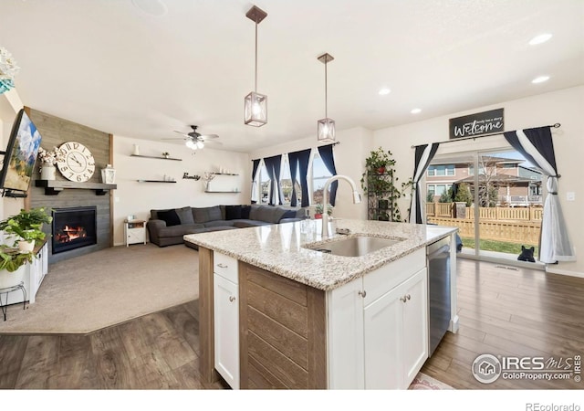 6504 Zimmerman Lake Rd, Timnath, CO 80547 - kitchen with stainless steel dishwasher, dark wood finished floors, white cabinets, open floor plan, and a kitchen island with sink