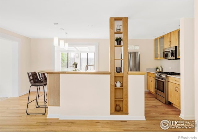 2085 Alpine Dr, Boulder, CO 80304 - kitchen with stainless steel appliances, a kitchen bar, light wood-style flooring, and glass insert cabinets