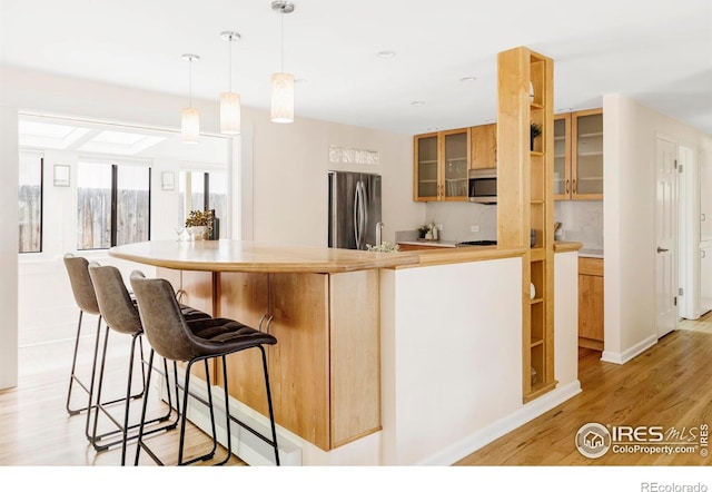 2085 Alpine Dr, Boulder, CO 80304 - kitchen with stainless steel appliances, light wood-style flooring, glass insert cabinets, a breakfast bar area, and pendant lighting