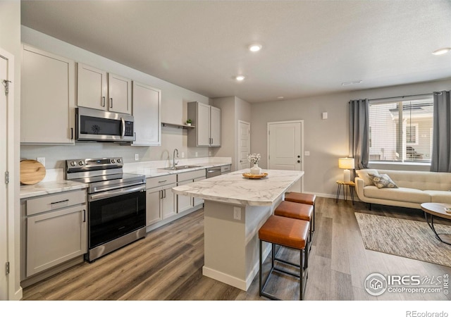 620 Apache Trl Unit 2, Ault, CO 80610 - kitchen with appliances with stainless steel finishes, a kitchen island, wood finished floors, a kitchen bar, and gray cabinets