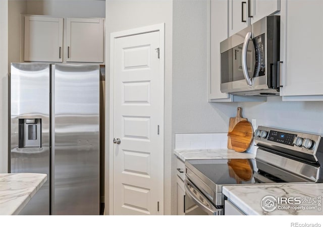 620 Apache Trl Unit 2, Ault, CO 80610 - kitchen featuring appliances with stainless steel finishes, white cabinetry, and light stone countertops