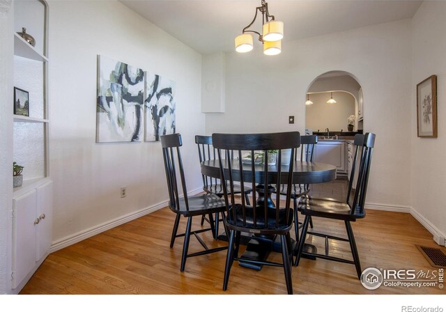 403 W Cannon St, Lafayette, CO 80026 - dining room featuring arched walkways, wood finished floors, and a chandelier