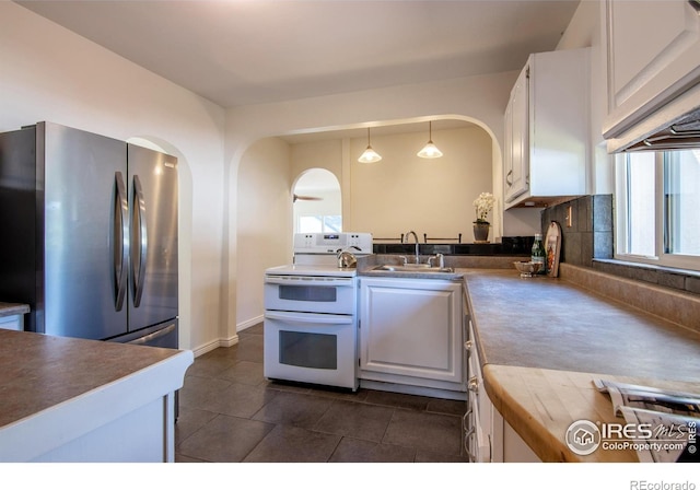 403 W Cannon St, Lafayette, CO 80026 - kitchen featuring double oven range, arched walkways, freestanding refrigerator, and white cabinets
