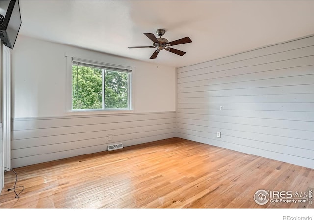 6864 Balsam St, Arvada, CO 80004 - unfurnished room with wooden walls, light wood-style floors, and a ceiling fan