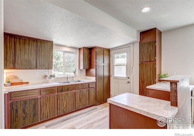 1343 E 7th St Unit 1, Loveland, CO 80537 - kitchen featuring a textured ceiling, light wood-style floors, brown cabinetry, light countertops, and recessed lighting