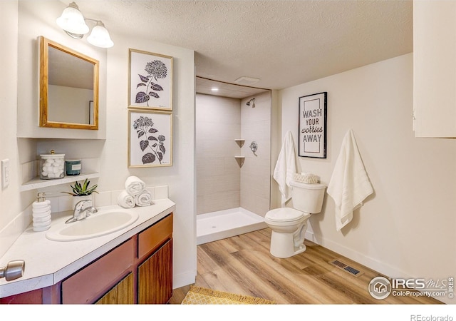 1343 E 7th St Unit 1, Loveland, CO 80537 - bathroom featuring wood finished floors, tiled shower, vanity, and a textured ceiling