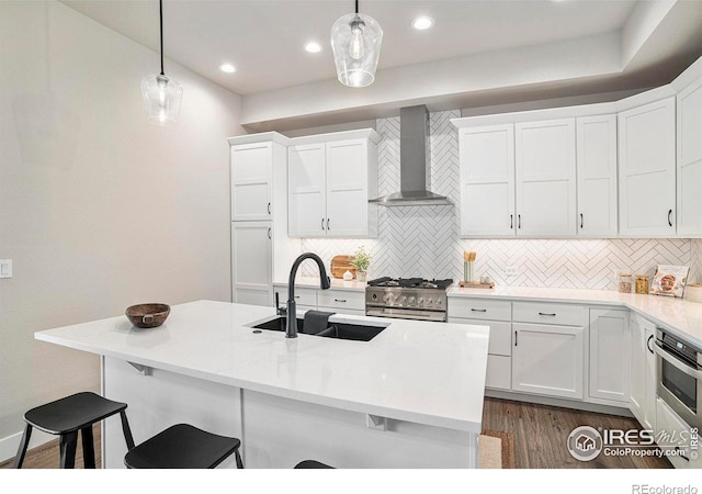 1550 Harebell St, Berthoud, CO 80513 - kitchen featuring wall chimney exhaust hood, stainless steel appliances, a breakfast bar, backsplash, and white cabinetry
