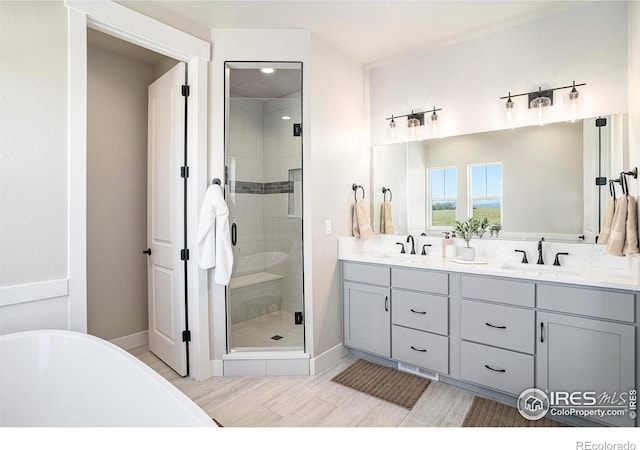 1550 Harebell St, Berthoud, CO 80513 - bathroom with double vanity, a shower stall, a freestanding tub, and wood finished floors