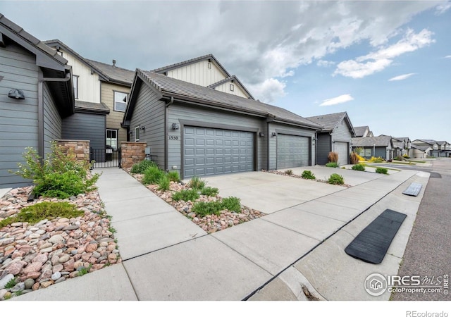 1550 Harebell St, Berthoud, CO 80513 - view of front of house with board and batten siding, a gate, a garage, concrete driveway, and a residential view