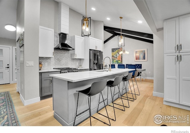 7146 Petursdale Ct, Boulder, CO 80301 - kitchen featuring wall chimney range hood, stainless steel fridge with ice dispenser, tasteful backsplash, light wood-type flooring, and an island with sink