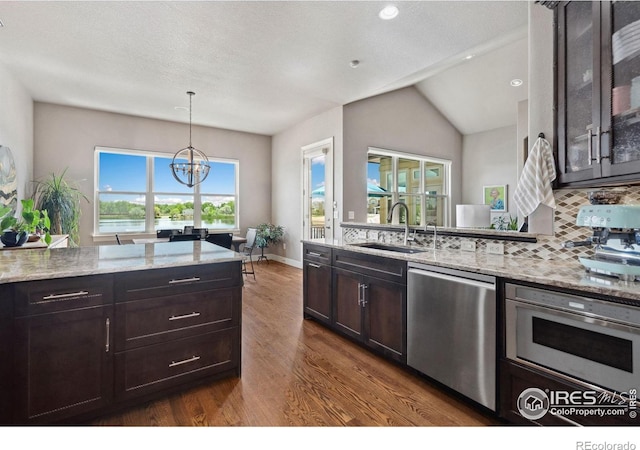 2055 Vineyard Dr, Windsor, CO 80550 - kitchen with appliances with stainless steel finishes, dark wood-style flooring, light stone counters, tasteful backsplash, and glass insert cabinets
