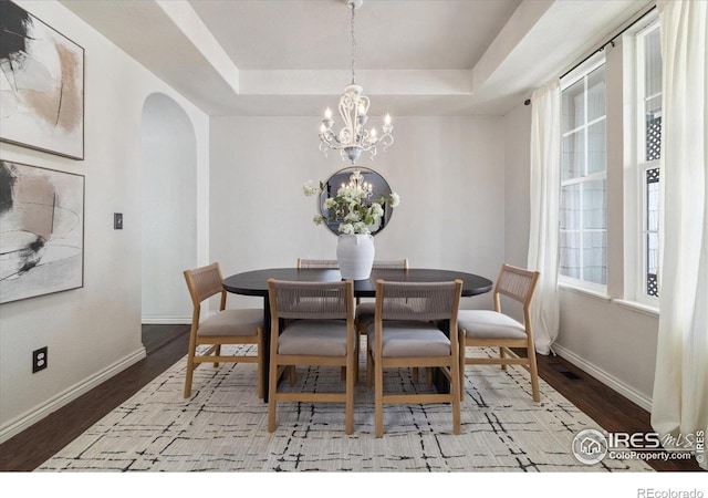 2133 Katahdin Dr, Fort Collins, CO 80525 - dining area featuring arched walkways, a raised ceiling, a chandelier, and plenty of natural light