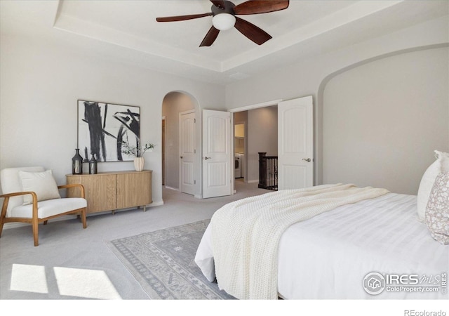 2133 Katahdin Dr, Fort Collins, CO 80525 - bedroom featuring arched walkways, light colored carpet, a raised ceiling, and ceiling fan