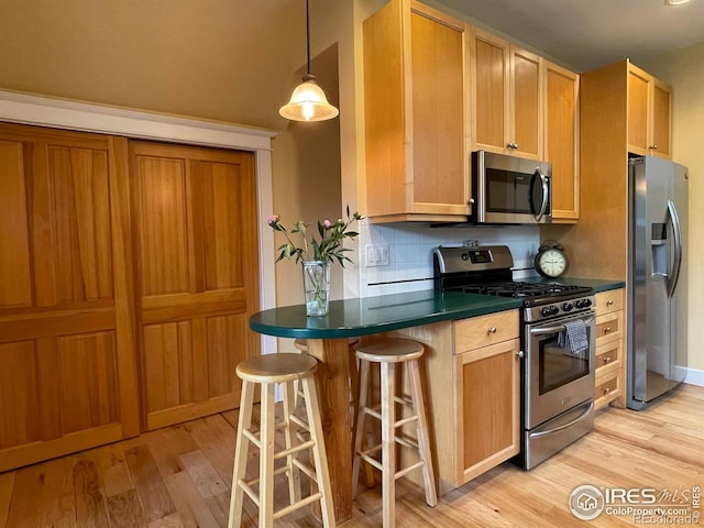 2204 Pine St, Boulder, CO 80302 - kitchen with appliances with stainless steel finishes, light wood-style flooring, dark countertops, a breakfast bar area, and backsplash