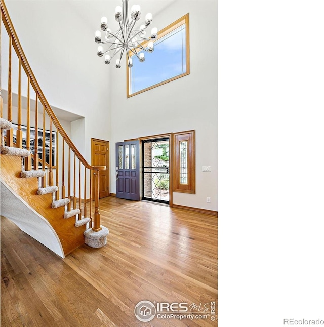14601 Akron St, Brighton, CO 80602 - foyer entrance featuring wood finished floors, a chandelier, stairway, and a towering ceiling