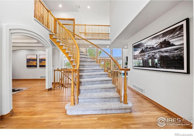 14601 Akron St, Brighton, CO 80602 - stairs featuring wood finished floors, arched walkways, a towering ceiling, and recessed lighting