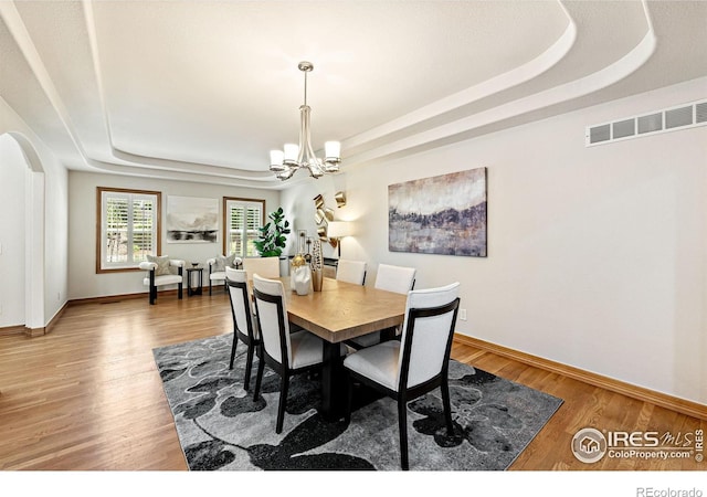 14601 Akron St, Brighton, CO 80602 - dining room featuring a tray ceiling, a chandelier, wood finished floors, and arched walkways