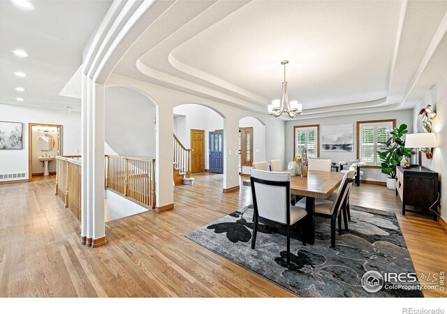 14601 Akron St, Brighton, CO 80602 - dining area with arched walkways, a raised ceiling, a chandelier, light wood-style floors, and recessed lighting