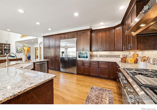 14601 Akron St, Brighton, CO 80602 - kitchen with appliances with stainless steel finishes, extractor fan, backsplash, light wood-style floors, and recessed lighting