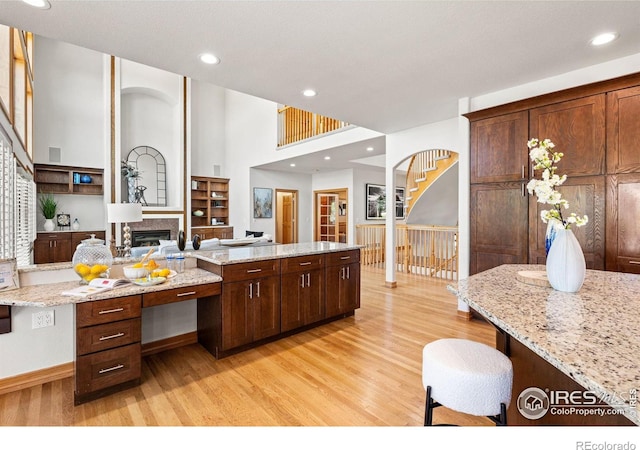 14601 Akron St, Brighton, CO 80602 - kitchen featuring light wood finished floors, a towering ceiling, light stone countertops, recessed lighting, and a kitchen breakfast bar