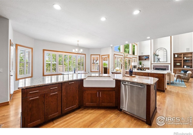 14601 Akron St, Brighton, CO 80602 - kitchen featuring dishwasher, light wood-style floors, a fireplace, a chandelier, and recessed lighting
