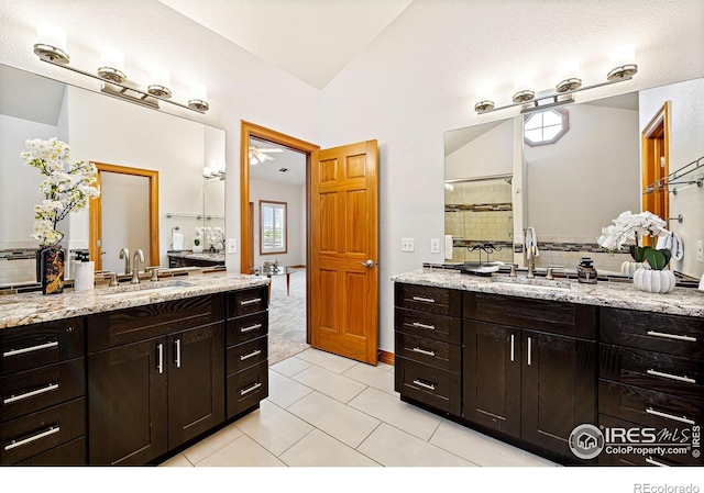 14601 Akron St, Brighton, CO 80602 - bathroom featuring two vanities, backsplash, tile patterned flooring, a tile shower, and vaulted ceiling