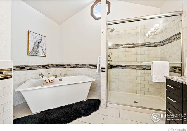 14601 Akron St, Brighton, CO 80602 - full bathroom with vaulted ceiling, tile patterned floors, a soaking tub, a shower stall, and tile walls
