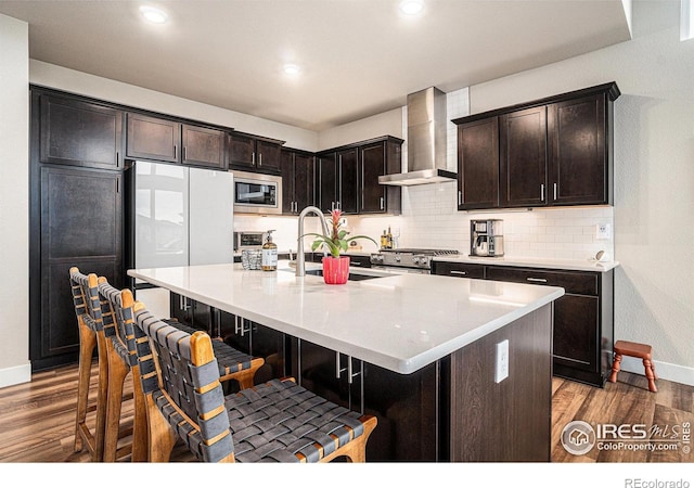 2716 San Cristobal Ct, Timnath, CO 80547 - kitchen with wall chimney range hood, appliances with stainless steel finishes, wood finished floors, tasteful backsplash, and recessed lighting