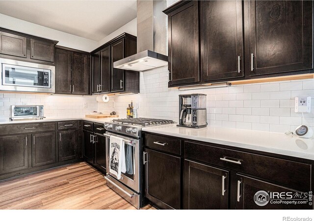 2716 San Cristobal Ct, Timnath, CO 80547 - kitchen with stainless steel appliances, wall chimney range hood, light wood finished floors, backsplash, and light countertops