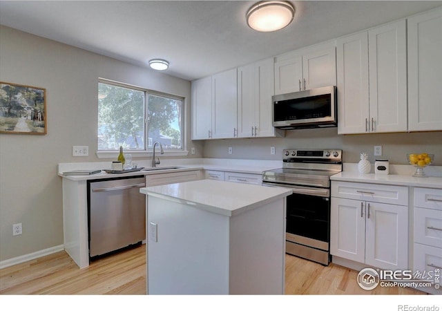 13382 Franklin St, Thornton, CO 80241 - kitchen with appliances with stainless steel finishes, light wood-style floors, light countertops, white cabinets, and a kitchen island