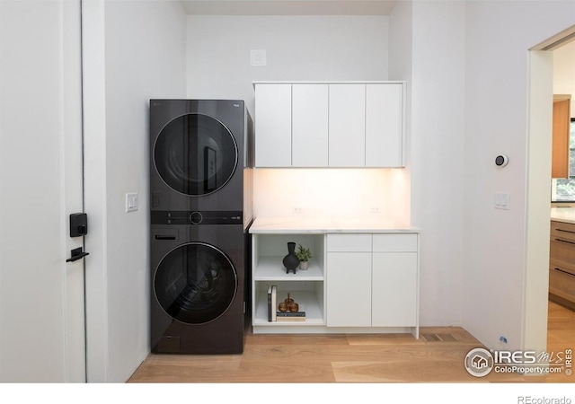 640 Iris Ave, Boulder, CO 80304 - laundry area featuring stacked washer / dryer, cabinet space, and light wood-type flooring